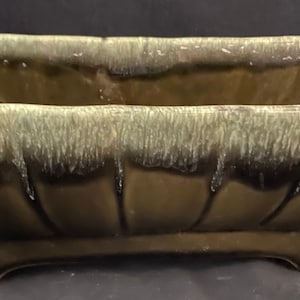 May include: A rectangular green glazed ceramic planter with a fluted design and four short legs.