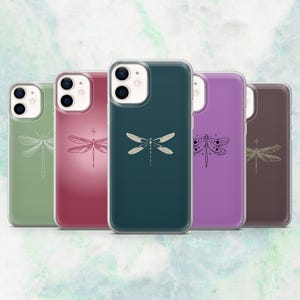 May include: Five phone cases in a row, each with a dragonfly motif. The cases are in green, red, teal, purple, and brown. The dragonfly designs range from simple outlines to more intricate illustrations. The cases are designed for a smartphone.