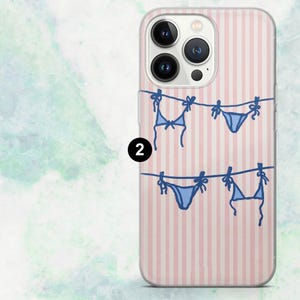 K&ouml;nnte beinhalten: Transparente Handyh&uuml;lle mit rosa-wei&szlig; gestreiftem Hintergrund. Die H&uuml;lle zeigt ein blaues Bikini-Design, das an einer W&auml;scheleine h&auml;ngt. Das Design wiederholt sich zweimal.