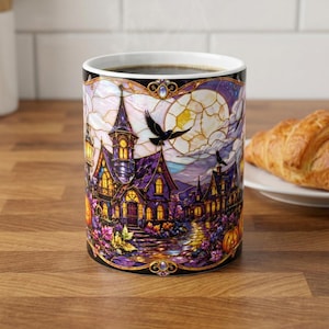 May include: A ceramic mug featuring a vibrant stained-glass style illustration of a dark, purple-toned gothic mansion at night. The design includes flying black crows, a large full moon, glowing yellow windows, and orange pumpkins in the foreground.