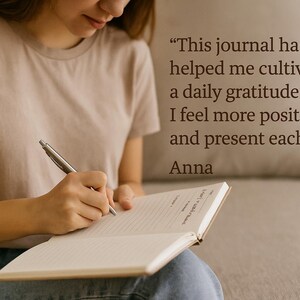 May include: A person writing in a journal with a silver pen. The journal is open, revealing lined pages. Text on the image reads: "This journal has helped me cultivate a daily gratitude habit. I feel more positive and present each day." - Anna.