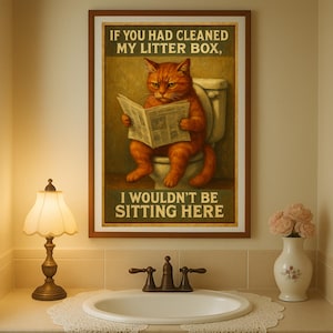Puede incluir: Un póster enmarcado muestra un gato naranja sentado en un inodoro, leyendo un periódico. El póster tiene el texto: "SI HUBIERAS LIMPIADO MI ARENERO, NO ESTARÍA SENTADO AQUÍ."