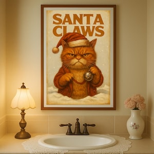 Op de afbeelding: Een ingelijste print met een oranje kat verkleed als de kerstman, met de tekst "SANTA CLAWS" erboven. De kat draagt een kerstmuts en jas, en houdt een bel vast. Het kunstwerk wordt boven een wastafel getoond.