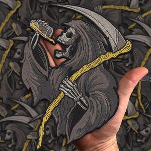 Może przedstawiać: Haftowana naszywka przedstawiająca Grim Reapera trzymającego kosę i but do ust. Naszywka jest gł&oacute;wnie szara, z ż&oacute;łtymi i beżowymi akcentami. Żniwiarz ma na sobie kaptur. Tło to powtarzający się wz&oacute;r tego samego projektu.