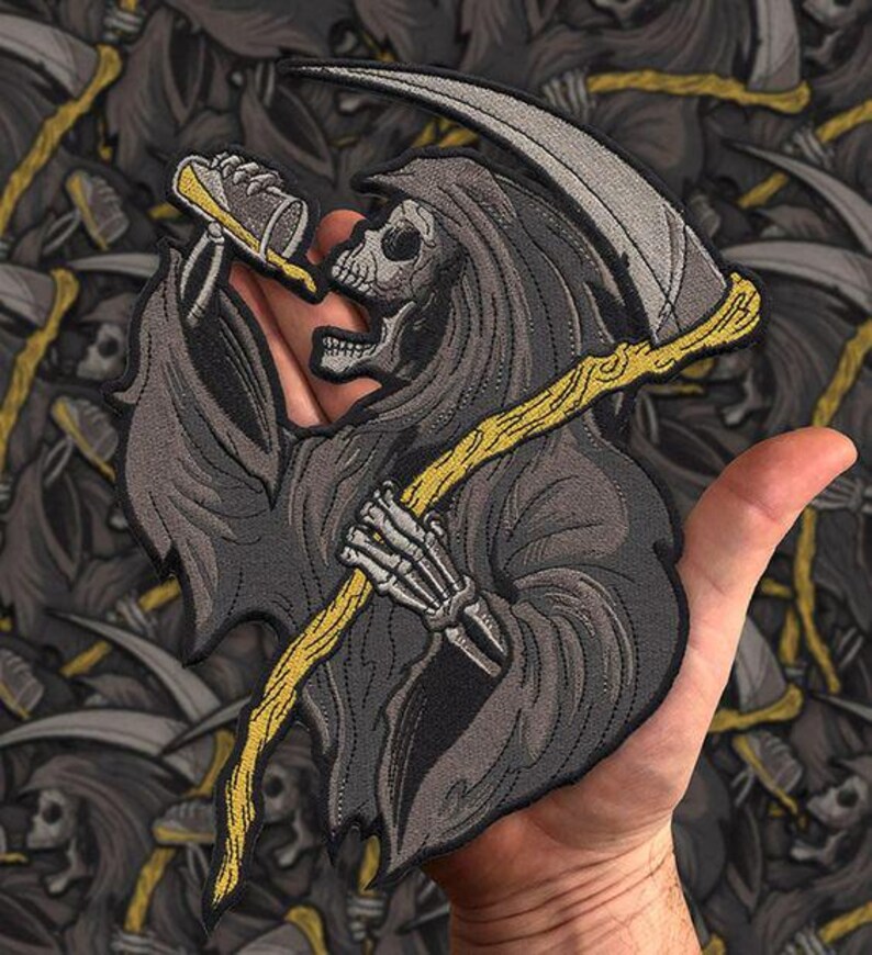 Może przedstawiać: Haftowana naszywka przedstawiająca Grim Reapera trzymającego kosę i but do ust. Naszywka jest gł&oacute;wnie szara, z ż&oacute;łtymi i beżowymi akcentami. Żniwiarz ma na sobie kaptur. Tło to powtarzający się wz&oacute;r tego samego projektu.