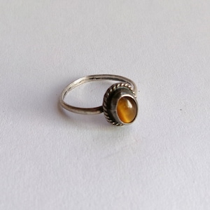 May include: A silver ring with a brown oval gemstone set in a silver bezel. The ring has a simple band and a textured bezel.