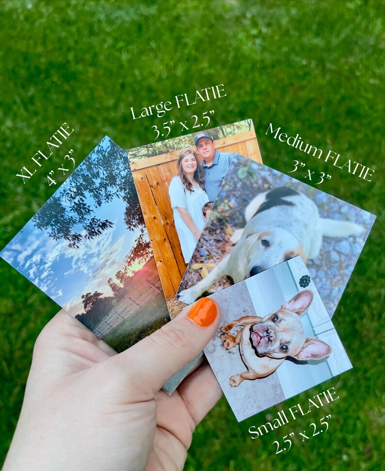 May include: A hand holds a collection of square and rectangular photos, labeled "XL FLATIE" (4" x 3"), "Large FLATIE" (3.5" x 2.5"), "Medium FLATIE" (3" x 3"), and "Small FLATIE" (2.5" x 2.5"). The photos feature images of a couple, a dog, and a landscape.