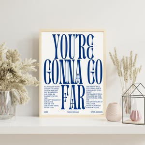 以下が含まれることがあります： クリーム色の背景に、紺色のテキスト「YOU'RE GONNA GO FAR」がプリントされた額入りのアートプリント。プリントには歌詞、アーティスト名、アルバムタイトルが含まれています。フレームは明るい木の色です。