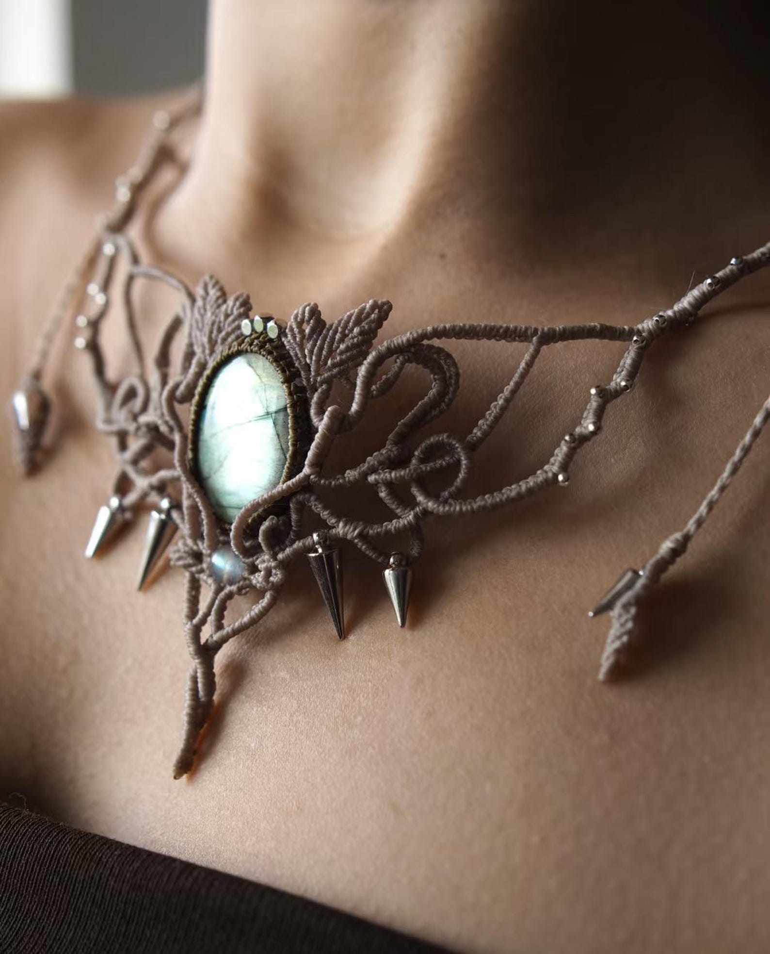 Close-up of labradorite crystal macrame choker with silver cone beads and botanical motifs.
