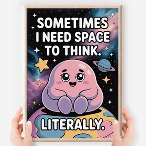 May include: A framed print with a whimsical space theme. The artwork features a cute, pink, blob-like character sitting on a planet, with the text "SOMETIMES I NEED SPACE TO THINK. LITERALLY." The background is a colorful galaxy.