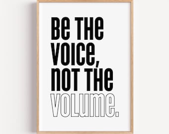 May include: A framed print with the text "BE THE VOICE, NOT THE VOLUME" in bold black letters. The words are centered on a white background, and the frame is a light wood color.