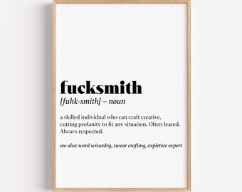 May include: A framed print with the word "fucksmith" in bold black font. The definition below describes a skilled individual who uses creative profanity. The print is in a light wood frame.