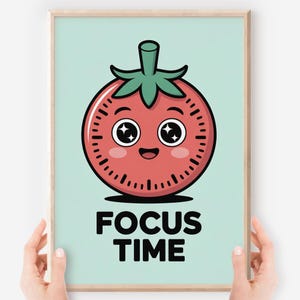 Op de afbeelding: Een ingelijste print met een cartoon tomatenontwerp. De rode tomaat heeft een klokgezicht, een groene stengel en de zwarte woorden "FOCUS TIME". De tomaat heeft een glimlachende uitdrukking en grote ogen, tegen een lichtblauwe achtergrond.