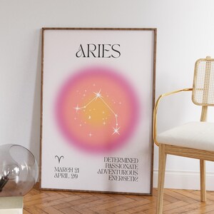 May include: A framed Aries zodiac sign art print. The artwork features the word "ARIES" in elegant script above a pink and yellow gradient circle with a constellation design. Additional text includes the Aries dates and personality traits.
