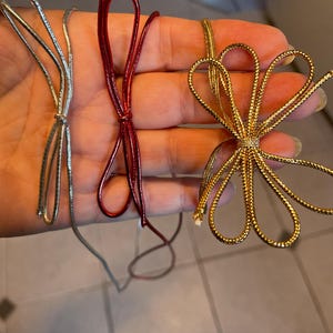 May include: Three different colors of metallic ribbon, silver, red, and gold, tied into bows.