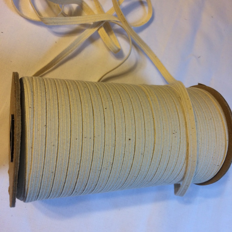 May include: A spool of off-white cotton elastic cord. The cord is wound around a cardboard spool.