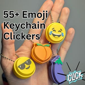 May include: Four emoji keychain clickers are shown, including a laughing face, a peach, a face with sunglasses, and an eggplant. The clickers are yellow, orange, and purple, with silver chain attachments. Text reads "55+ Emoji Keychain Clickers".