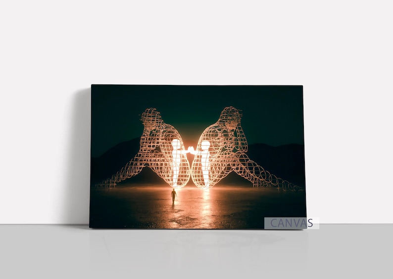 May include: Canvas art print featuring two large, illuminated wireframe figures facing each other, with a small person standing between them. The figures are in a seated position, with their heads resting on their hands. The background is a dark, moody landscape.