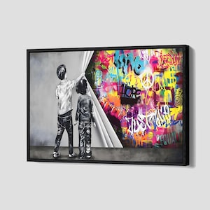 Op de afbeelding: Ingelijst kunstwerk met twee kinderen die een gordijn opentrekken om een levendige graffiti-muur te onthullen. De graffiti bevat kleurrijke tekst en symbolen, waaronder het woord "HOPE". Het kunstwerk staat tegen een neutrale grijze achtergrond.