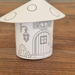 Puede incluir: Una caprichosa casa de champi&ntilde;ones de papel en blanco y negro. La casa tiene una puerta redonda, una ventana y una l&aacute;mpara decorativa. El sombrero del champi&ntilde;&oacute;n tiene c&iacute;rculos blancos. Perfecto para colorear o manualidades.