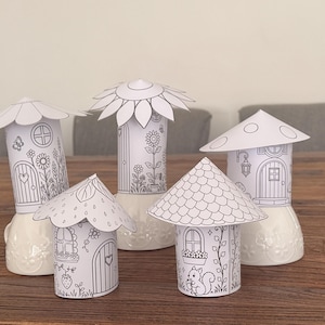 Puede incluir: Cinco casas de hadas de papel sin colorear con varios dise&ntilde;os de techo, incluyendo una flor, una seta y una fresa. Cada casa presenta un detallado dibujo lineal de puertas, ventanas y detalles florales, sobre bases de cer&aacute;mica blanca.