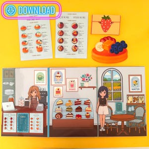 May include: A colorful diorama of a cafe and food items. Includes menus for pancakes and acai bowls, a strawberry-shaped envelope, and a dessert with fruit. The cafe features a cashier, display of cakes, and a customer.