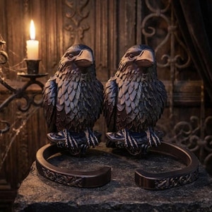 Peut inclure: Deux sculptures d'oiseaux en bronze foncé avec des textures de plumes détaillées et des bases incurvées. Les oiseaux ont une apparence réaliste avec des becs pointus et sont exposés sur une surface en pierre. L'arrière-plan comprend des bougies et un mur décoratif.