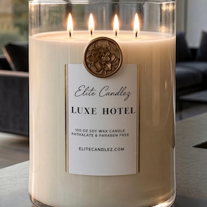 May include: A large clear glass jar candle with four lit wicks and off-white wax. A white label reads Elite Candlez LUXE HOTEL 100 OZ SOY WAX CANDLE PHTHALATE & PARABEN FREE ELITECANDLEZ.COM, topped with a circular gold-toned floral wax seal emblem.