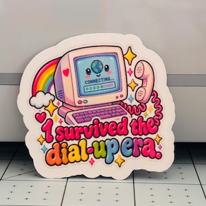 May include: A die-cut sticker featuring a retro computer with a smiling face on the screen displaying the text CONNECTING... and a loading bar. A pink telephone handset is attached by a cord. The text reads I survived the dial-up era in colorful letters.