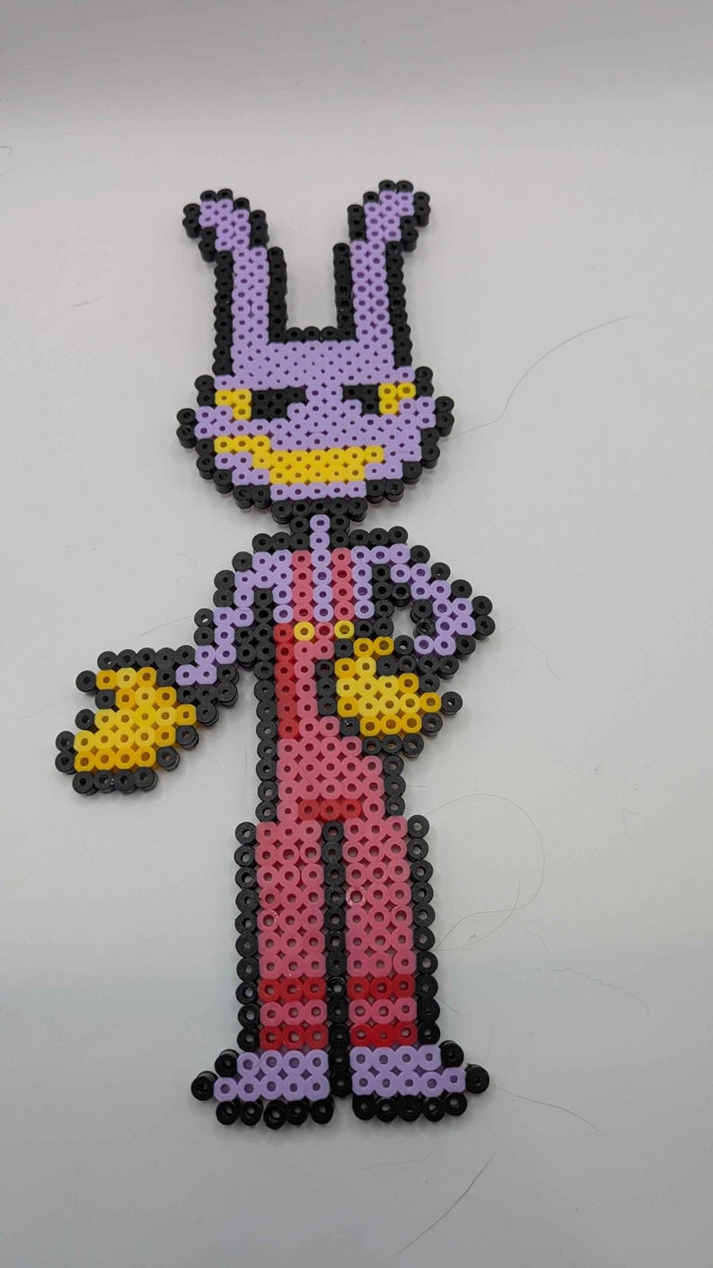 May include: A pixel art figure made from colorful plastic beads. The figure has a purple head with yellow accents, a pink body, and black and yellow arms. The figure is standing with its arms out.