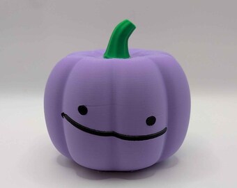 Puede incluir: Una figura de calabaza de color morado claro con un tallo verde brillante. La calabaza presenta un rostro de estilo sencillo dibujado a mano, compuesto por dos pequeños ojos negros circulares y una amplia línea negra curva que sonríe.