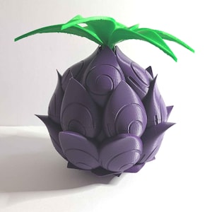 May include: A 3D-printed purple fruit with green leaves. The fruit has a textured surface with swirling patterns and a spiky, layered design. The green leaves are smooth and extend outward from the top of the fruit.
