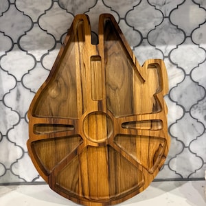 Peut inclure: Plateau de service en bois en forme de vaisseau spatial Millennium Falcon. Le bois brun clair présente un motif de grain naturel. Il comporte plusieurs compartiments et une section centrale circulaire, idéal pour les collations.