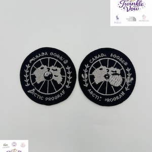 以下が含まれることがあります： 白の刺繍テキストと地図のデザインが施された、2つの円形の黒いパッチ。テキストは「CANADA GOOSE」と「ARCTIC PROGRAM」と書かれています。これらのパッチは、衣類やアクセサリー用である可能性があります。