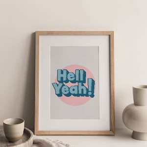 May include: A framed print with a light blue and white graphic that says "Hell Yeah!" in a retro font. The graphic is on a pink circle against a light gray background.