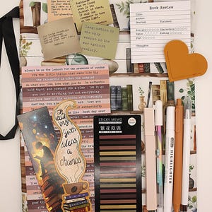 May include: A collection of stationery and book-related items arranged on a patterned pouch. Includes pens, highlighters, sticky notes, bookmarks, and quote cards. The text on the bookmark says "Reading gives ideas a chance." The pouch has a zip closure.