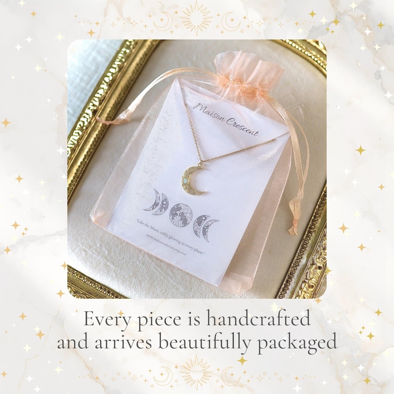 May include: A gold crescent moon necklace on a fine chain, displayed in a sheer, peach drawstring bag. The bag contains a card with moon phase illustrations and the text "Maison Crescent."
