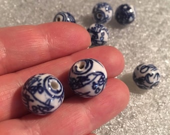Puede incluir: Una colección de cuentas de cerámica blanca con patrones florales azules y blancos. Las cuentas tienen un agujero en el centro para enhebrar.