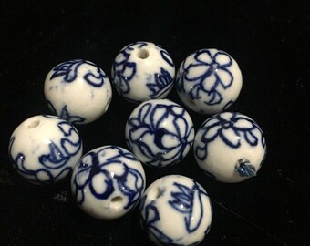 Puede incluir: Ocho cuentas de cerámica blanca con diseños florales azules. Las cuentas tienen un agujero en el centro para enhebrar.