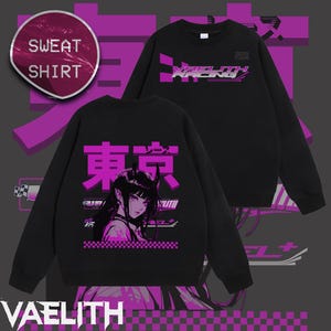 Op de afbeelding: Zwart sweatshirt met een grafisch ontwerp met een gestileerd anime-personage met hoorns, het woord "東京" in roze en de tekst "VAELITH RACING 2025 TOUR". Een ronde sticker leest "SWEAT SHIRT".