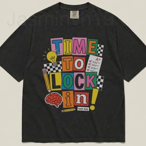 May include: A black t-shirt with a colorful graphic that reads "TIME TO LOCK IN!" with a lightbulb, pencil, brain, and test paper illustrations. The words "test day" are also included.
