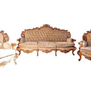 May include: A three-piece furniture set consisting of a sofa, a loveseat, and an armchair. Each piece features a light brown tufted fabric upholstery, ornate carved wooden frames with curved details, and exposed wooden legs with scrollwork.