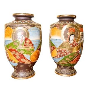 May include: Two matching brown ceramic vases featuring hand-painted figures in traditional attire with gold accents. Each vase displays a detailed scene with a central character surrounded by landscape elements, finished with a gold rim and base.