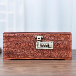 May include: A rectangular wooden box with a floral carved design and a combination lock. The box is a rich brown color and has a metal clasp and combination lock. The floral pattern covers the entire surface of the box.