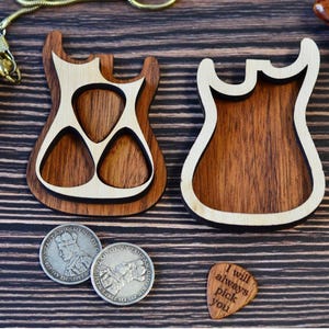 Könnte beinhalten: Zwei Gitarrenplektrumhalter aus Holz mit hellem Holzrand und dunklem Holzinnenraum. Ein Halter hat drei plektrumförmige Aussparungen. Zwei Silbermünzen und ein Gitarrenplektrum mit dem Text "I will always pick you" sind ebenfalls vorhanden.