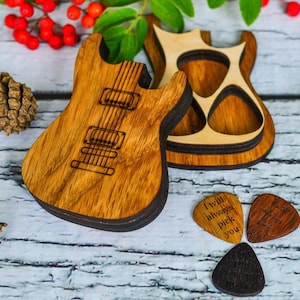 Könnte beinhalten: Gitarrenförmige Holzbox und Plektren. Die Box ist aus hellem und dunklem braunem Holz gefertigt und hat ein Gitarrendesign. Die Plektren sind braun und schwarz, mit dem Text "I will always pick you".