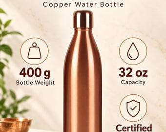 Puede incluir: Una botella de agua de cobre metálico con acabado liso y tapa a juego. El texto dice: SUVIRA, Quality in Every Detail, Copper Water Bottle, 400 g Bottle Weight, 32 oz Capacity y Certified Bottle. Los iconos muestran un peso, una gota y un escudo.