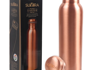 Puede incluir: Una botella de agua de cobre con una tapa de rosca a juego, junto a su caja negra. La caja presenta la marca "SUVIRA" y las palabras "PURE COPPER BOTTLE". La botella y la tapa tienen un acabado metálico brillante. La caja también dice "MADE IN INDIA".