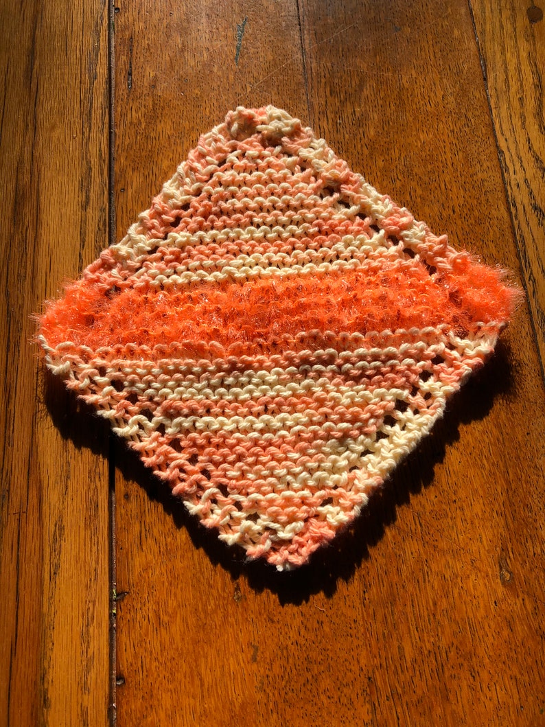 May include: A knitted dishcloth with a pink and white striped pattern and a fuzzy orange border.