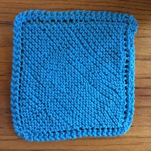 May include: A bright blue knitted dishcloth with a simple stitch pattern and a white border.